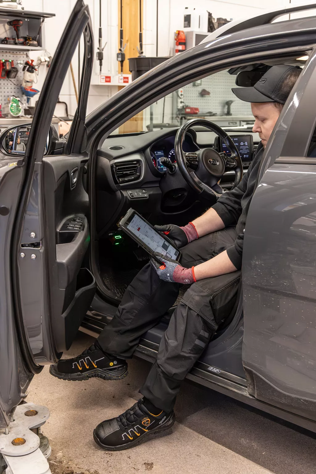 Technician using TEGERA Oil Grip 8855 safety gloves and JALAS Exalter safety shoes during car maintenance in a workshop.